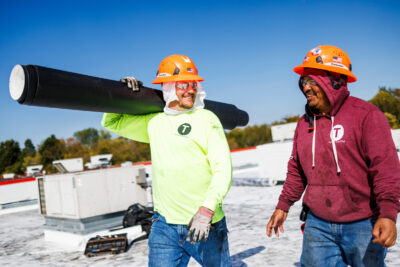 two men working on a commercial roof repair project